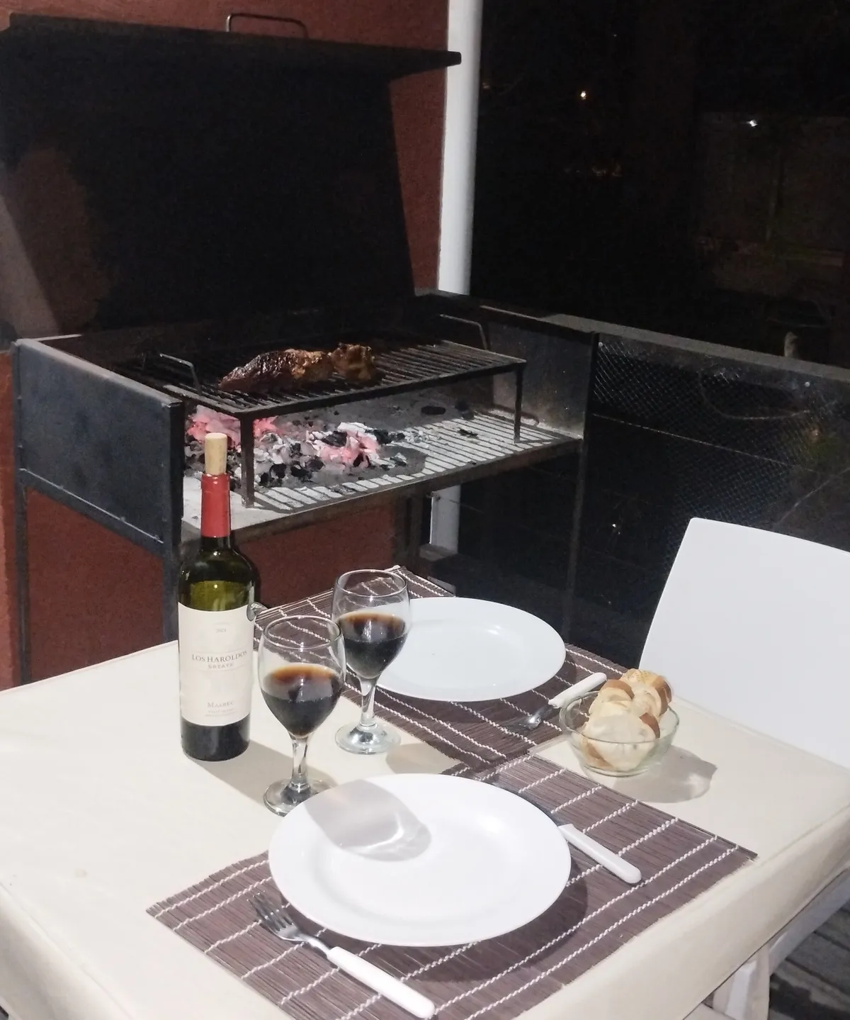 La parrilla del balcón encendida, con la mesa puesta